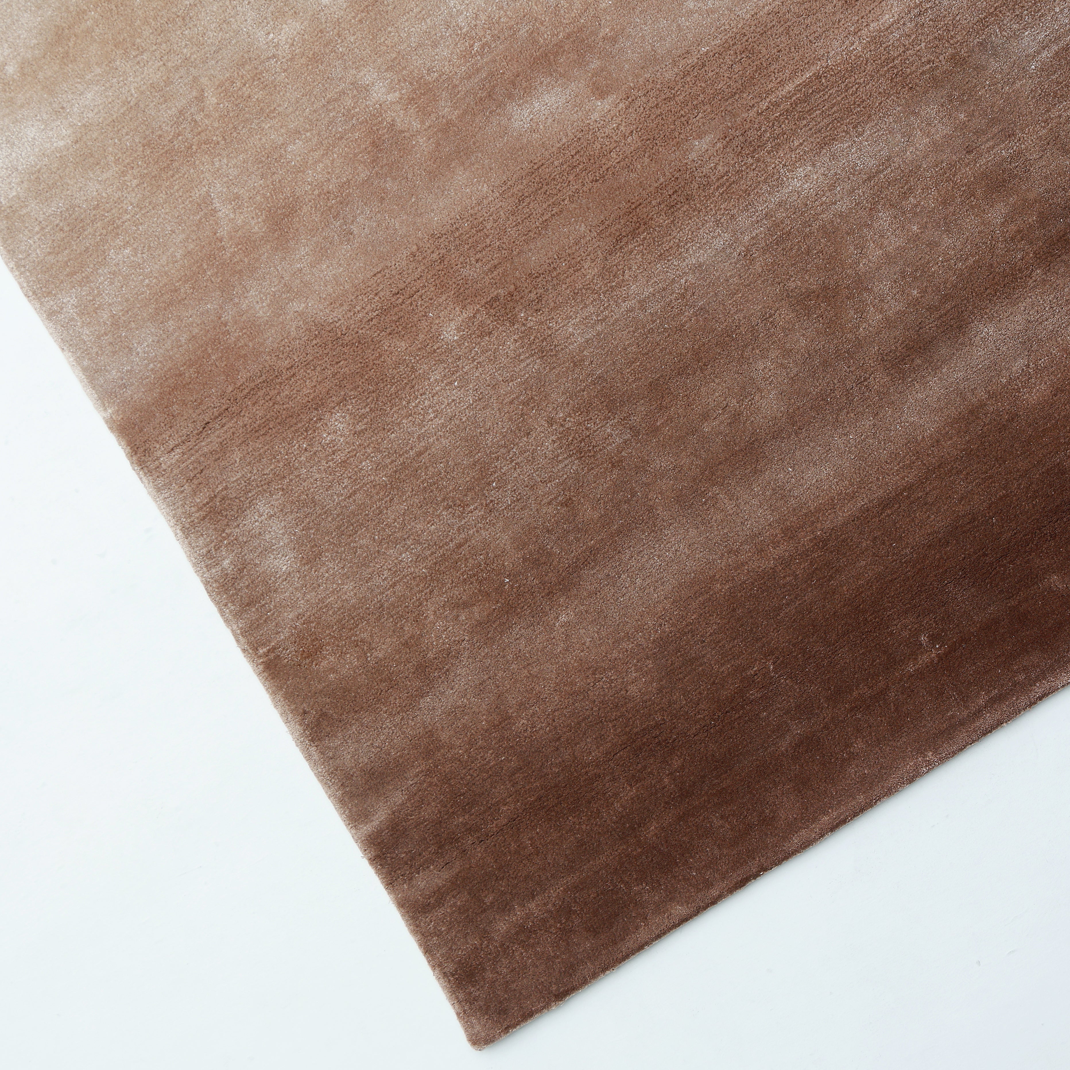A close-up of the RAMSHA HOME Caramel Ombre Handmade Area Rug - HTV 26 (300x400 cm) on a white surface, showing its rectangular hand-tufted design with a gradient fading from light to dark brown diagonally.