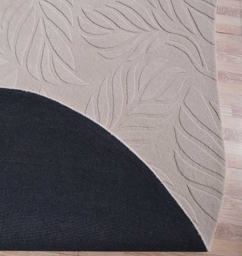 The RAMSHA HOME Premium Off-White Area Carpet - HTW 115 (200x300 cm) is partially lifted to show a black non-slip rug pad underneath on a light wood floor.