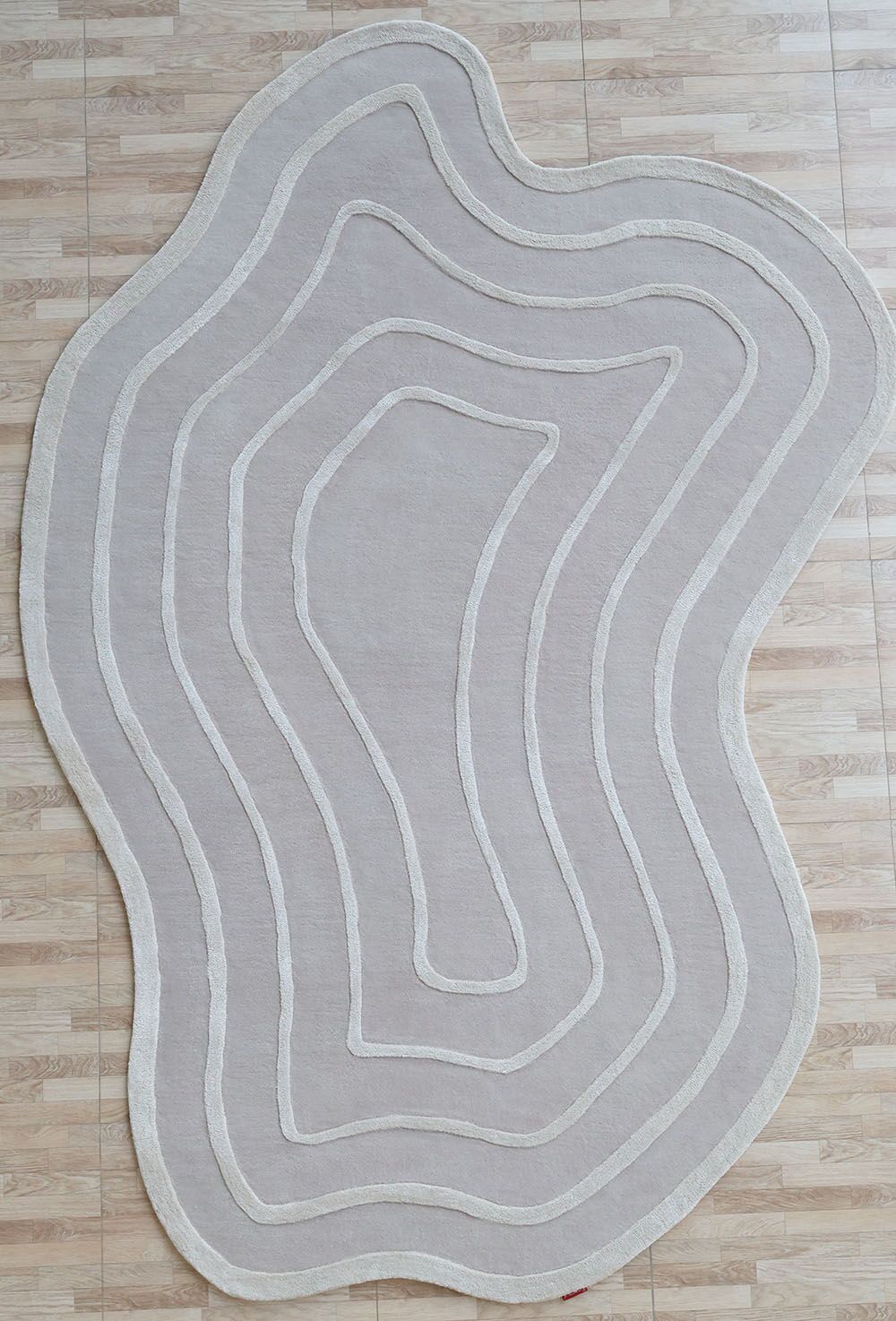The Beautiful Off White Handmade Rug - HTWV-112 (200x300cm) by RAMSHA HOME, featuring wavy lines and a topographic map look, sits on a light wood floor.