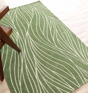 The RAMSHA HOME Leaf Vein Line Pattern Green & Ivory Rug – KD 015, made of polyester, adds natural charm and comfort with its wavy leaf-like design, shown here on a light wood floor beside a wooden chair with a woven cane seat.