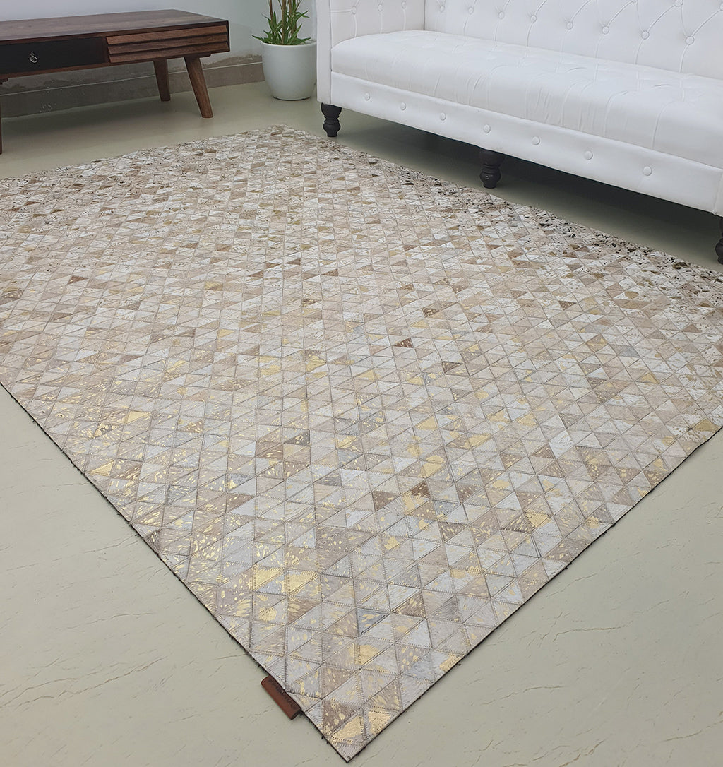 The Amazing Grey & Tan Color Playroom Leather Rug - LR 006 with a geometric design lies on a light floor in a modern living room, beside a white tufted sofa, wooden coffee table, and potted plant.
