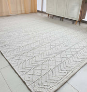 The RAMSHA HOME White Rectangle Woven Area Rug And Carpet For Living Room, Bedroom SR-022 adds a light, modern touch with its textured geometric pattern to a bright room featuring tiled floors, sheer curtains, and a white cabinet.