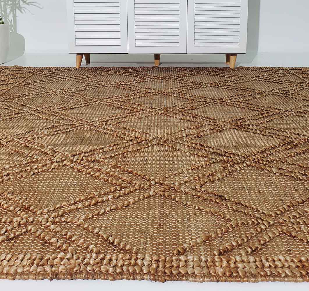 A close-up of the RAMSHA HOME Floor Woven Living Room Rug SR-019 in natural color and rectangular shape, featuring a geometric diamond pattern, placed on the floor before a white cabinet with wooden legs.