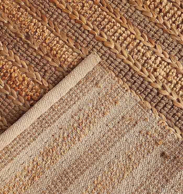 A close-up of the RAMSHA HOME Jute Woven Home Decor Rug Natural Color SR-032, featuring braided and textured patterns in beige and brown, adds a rustic, earthy charm to any room.