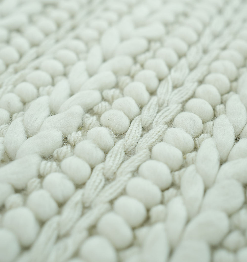 Close-up of the RAMSHA HOME Natural White Woven Rug For Home Decore SRN-028, featuring chunky off-white yarn and a braided, textured pattern with thick loops reminiscent of an ivory wool rug.